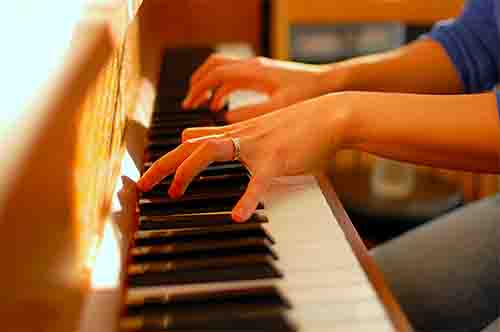inverted-chords-on-piano Two Hands Playing a Brown Piano